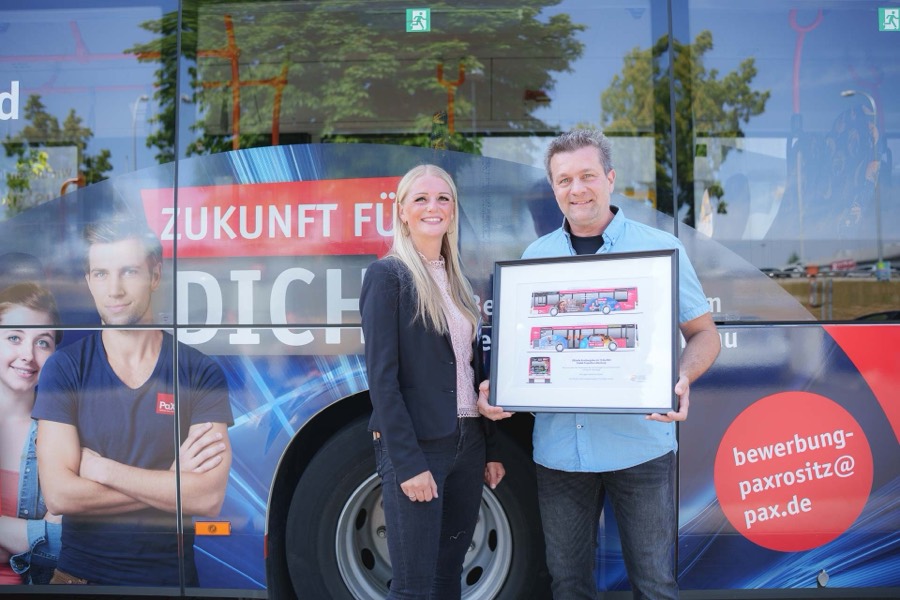 Übergabe eines Bilderrahmens vor einem Bus