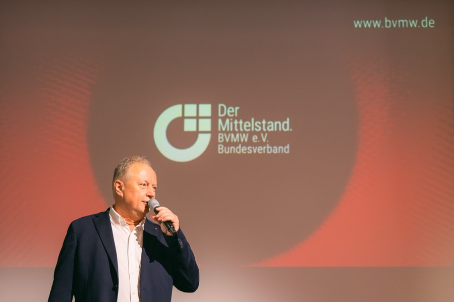 Rede vor dem BVMW-Logo